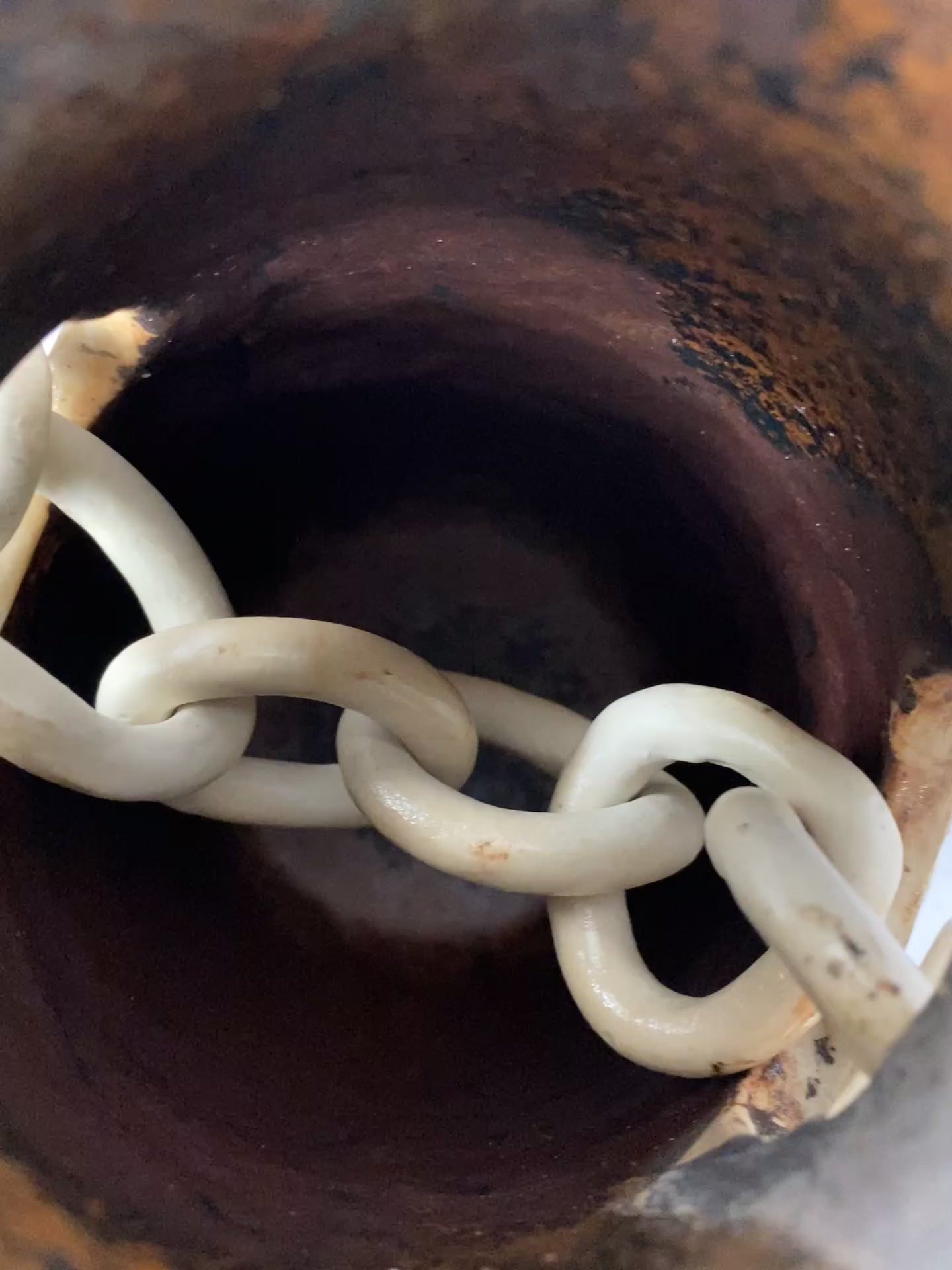 Load video: A wheel thrown vase made from porcelain clay, with a hand formed porcealin chain through the center.